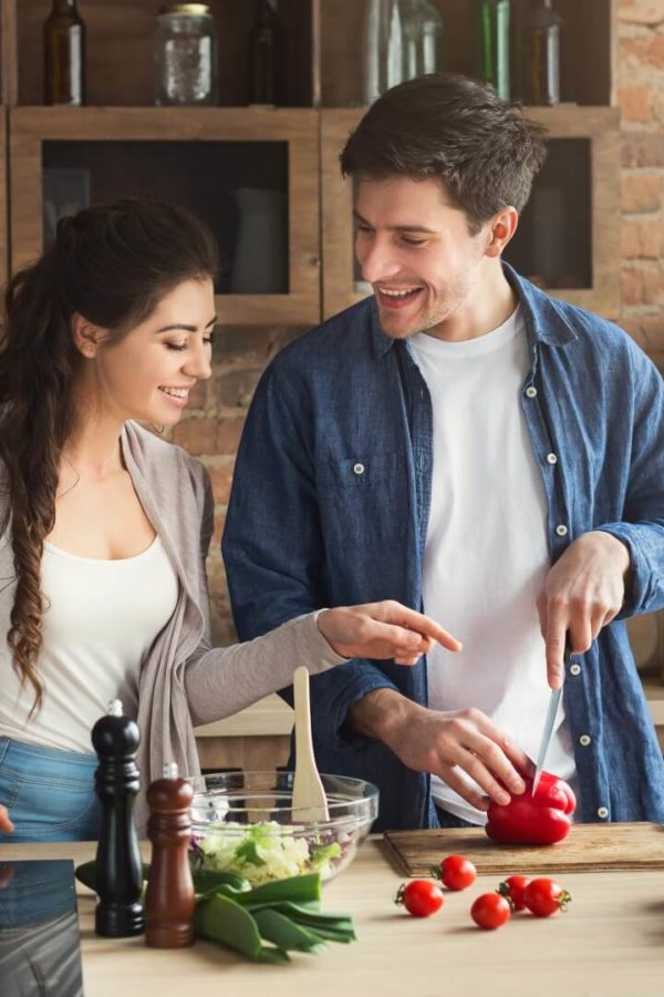 A happy young couple is cooking together in their kitchen.