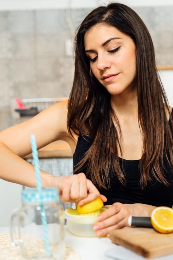 Mlada ženska ožema sok limone za pripravo limonade, saj limone vsebujejo veliko vitamina C.